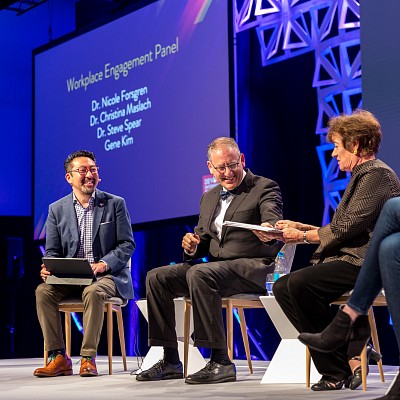 Event photography capturing a panel of experts on stage speaking at Devops London