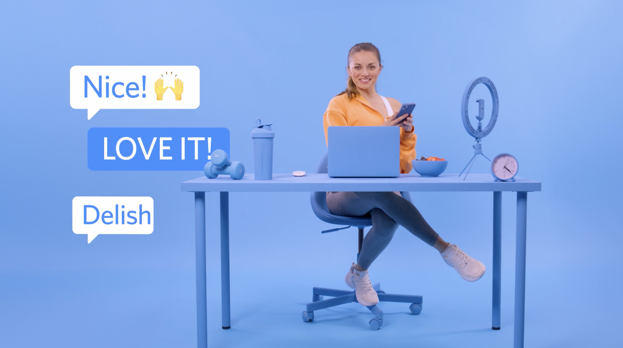 A person sits at a desk with a laptop, smartphone, and smoothie, surrounded by positive message bubbles saying Nice!, LOVE IT!, and Delish. The setting, perfect for a creative mind from a video production agency, is in harmonious shades of blue.