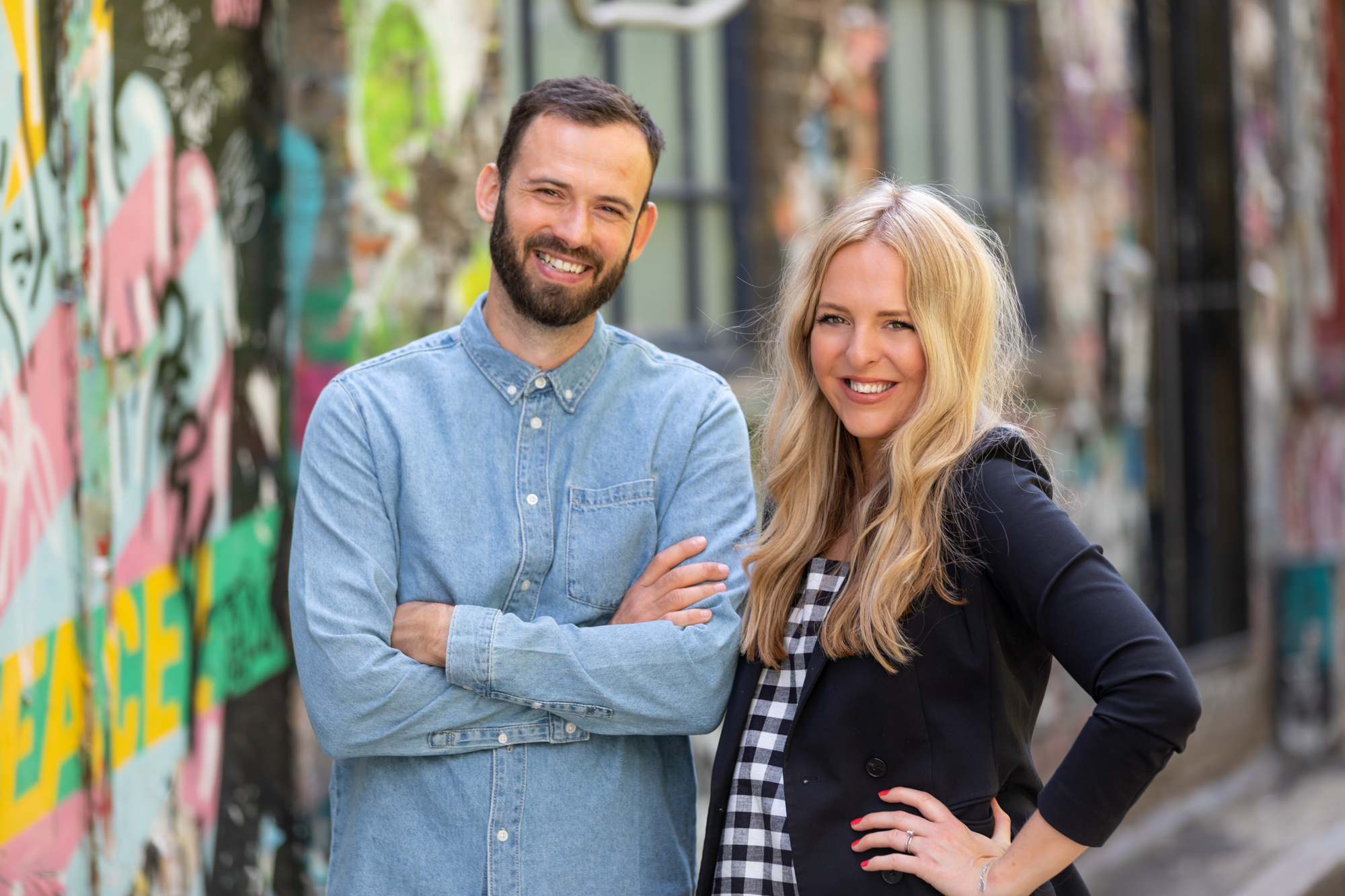 male and female founder of mhf video production company smiling to camera in front of graffiti wall