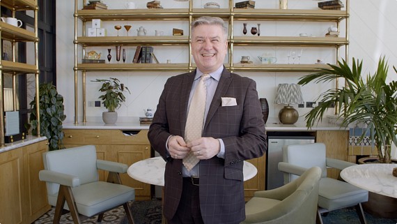 Male in a suit laughing to camera in a hotel setting
