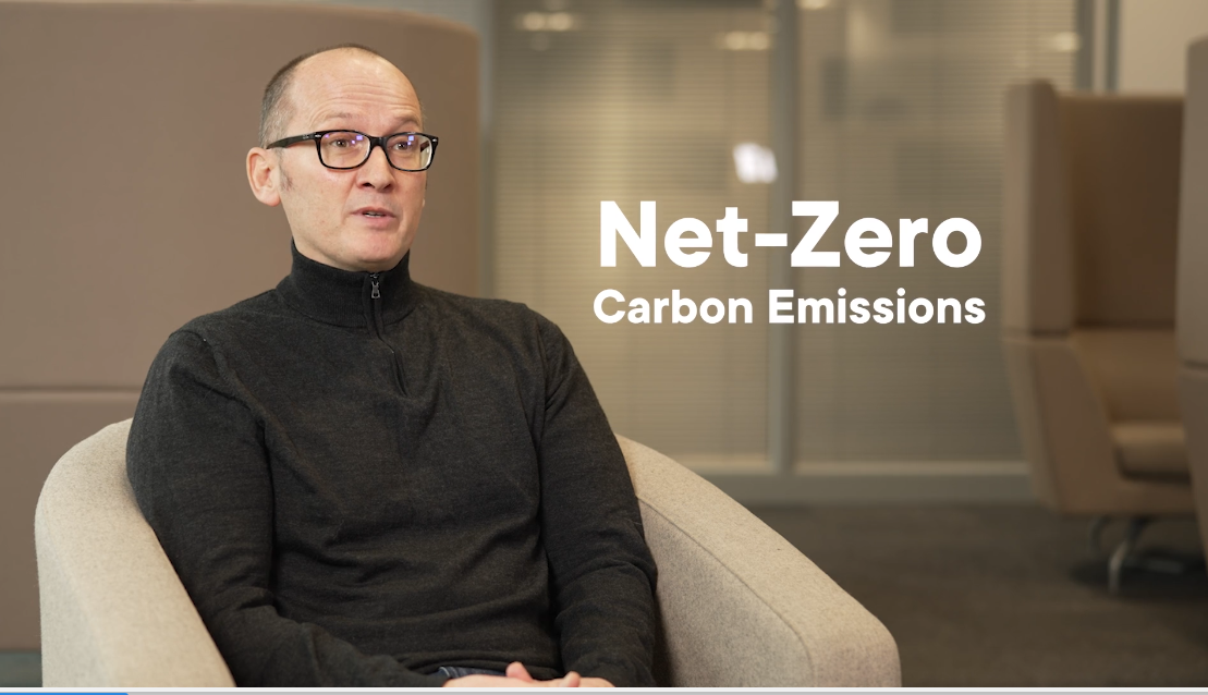 Man wearing glasses sitting in chair talking about net zero