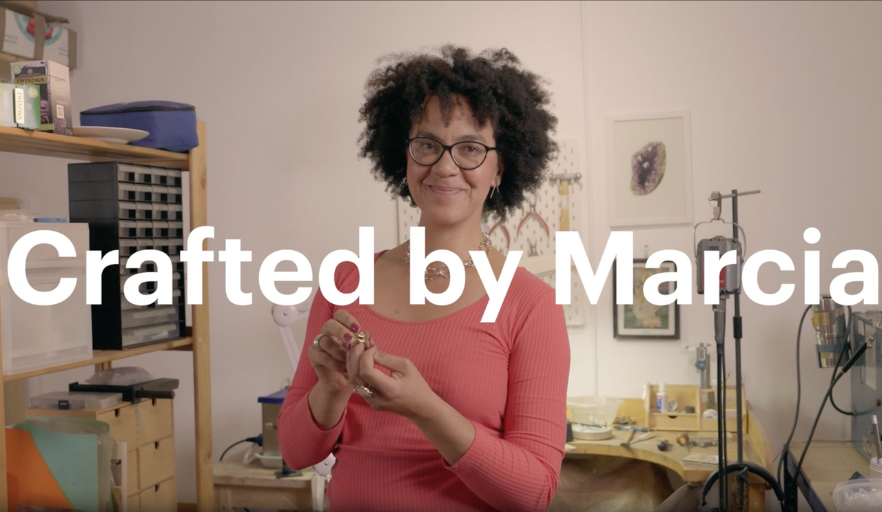Smiling woman in a workshop holding a handcrafted item, with on-screen text reading “Crafted by Marcia” — representing authentic, maker-led social media video content.