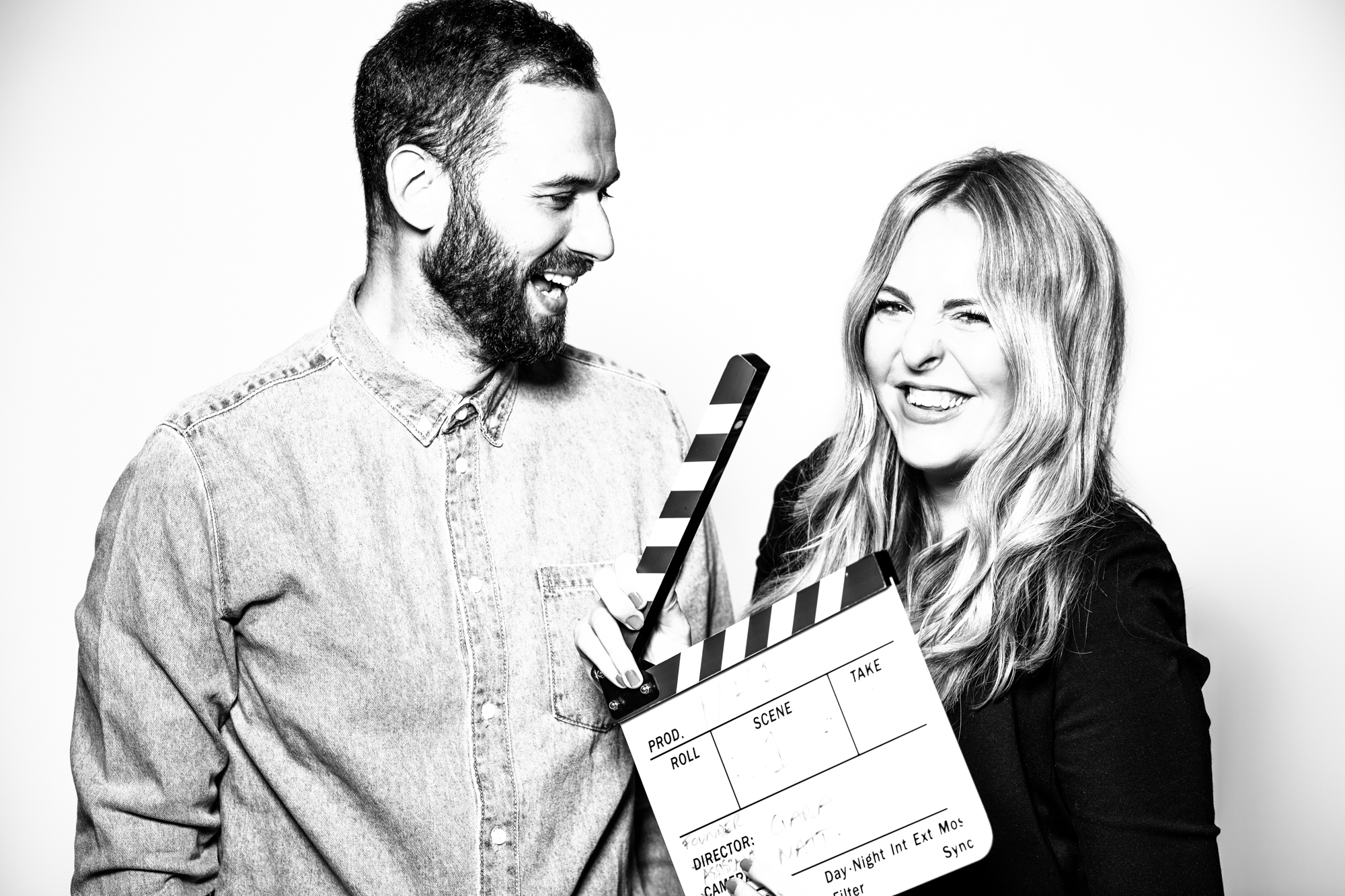 Black and white photo of male and female holding a clapperboard