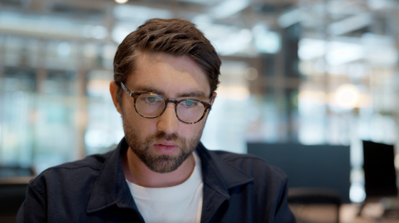 A focused man intently working on his laptop, his expression showing deep concentration as he engages with his task.