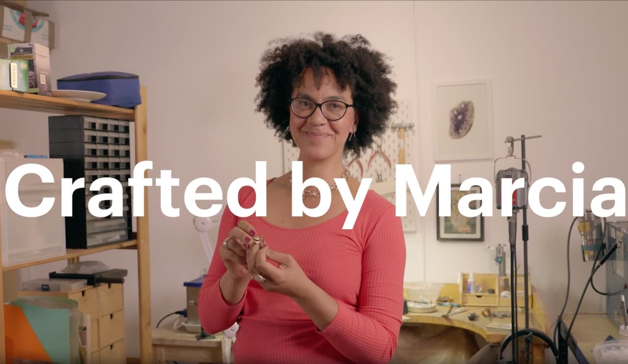 Etsy maker holding a pair of handmade earrings in her studio
