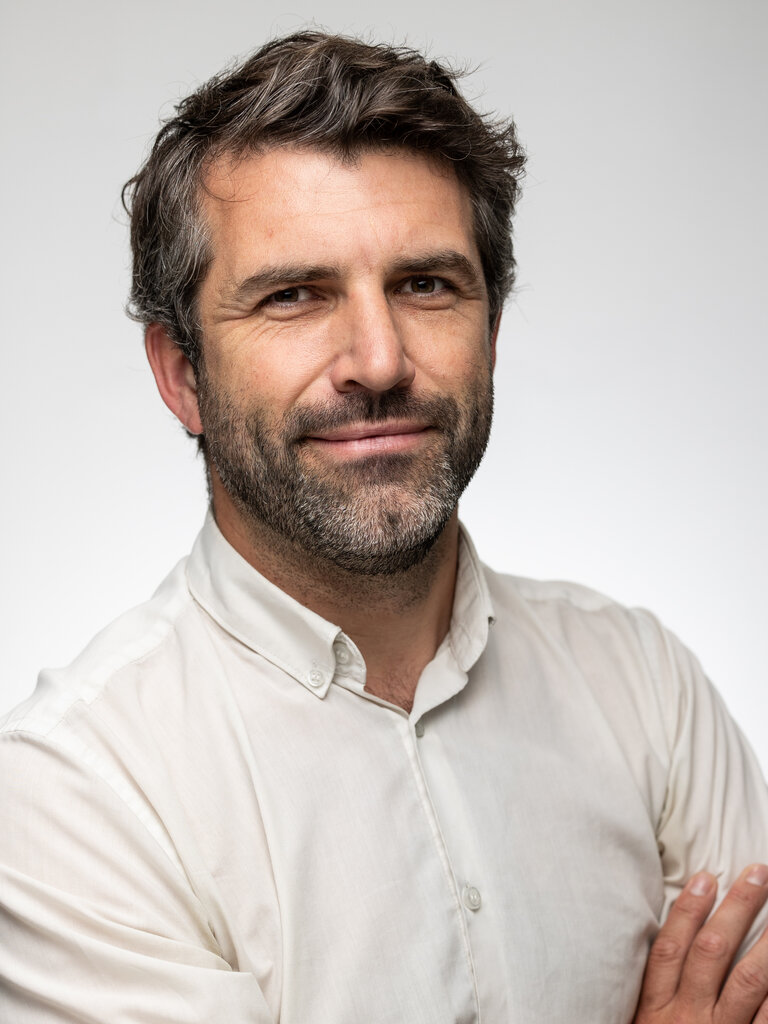 Headshot of a man with grey hair against a grey background.