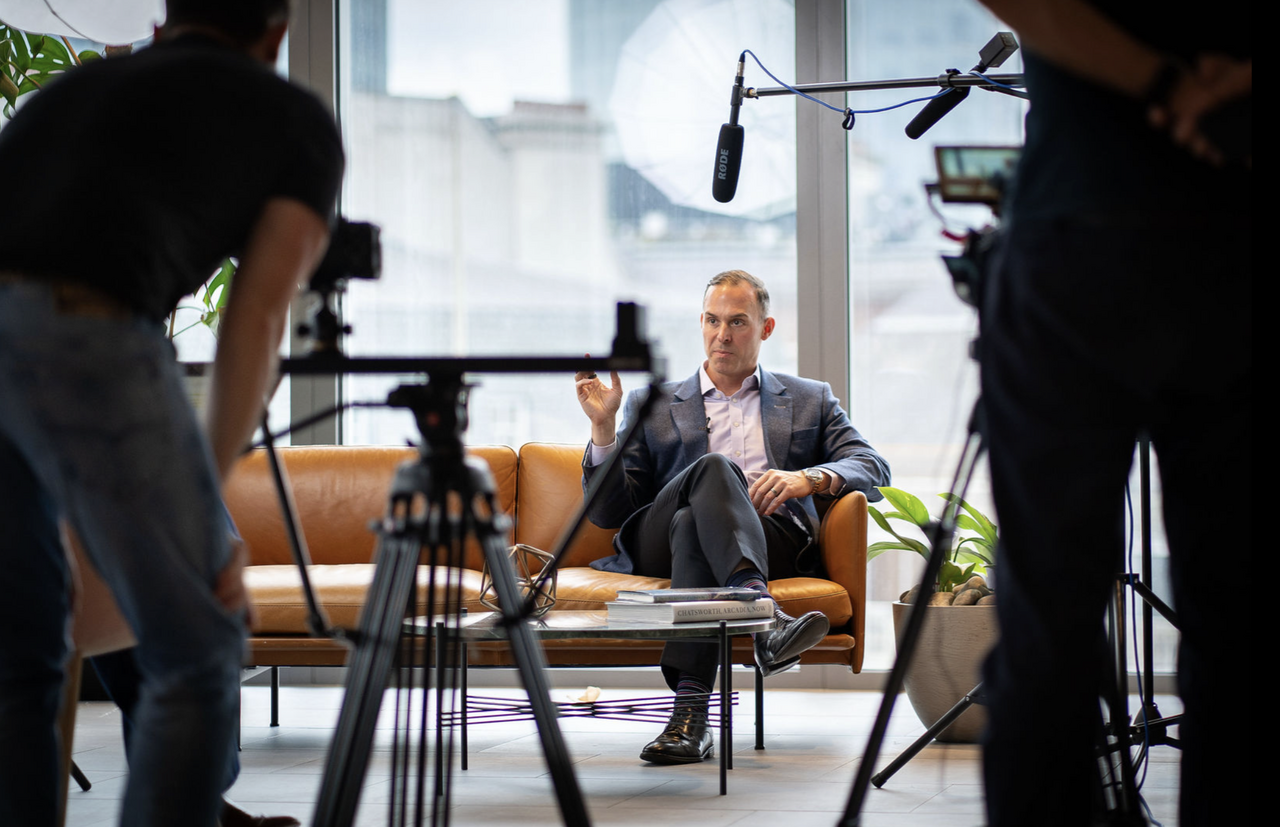 Behind-the-scenes of an executive being filmed during a professional corporate interview with camera crew and lighting