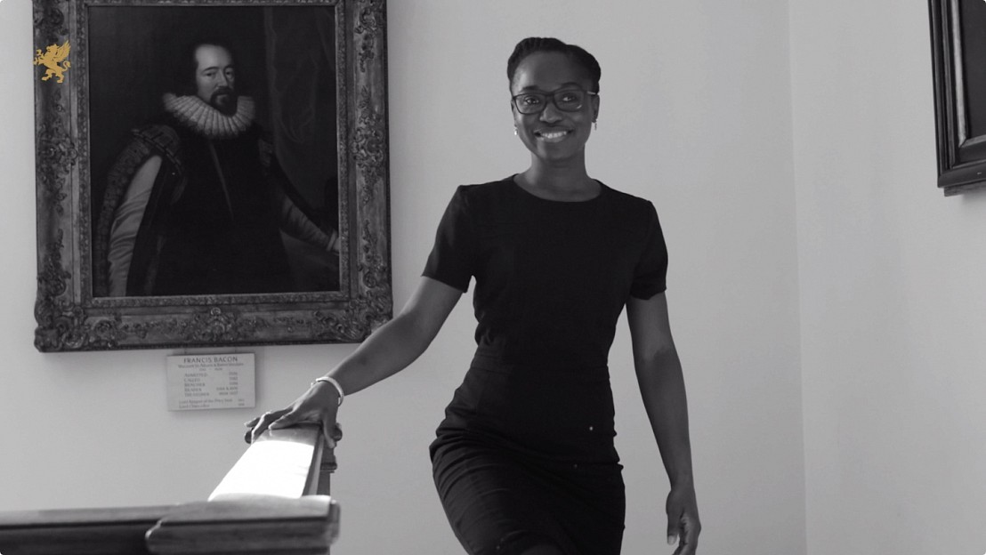 Black female wearing glasses walks up staircase of Grays Inn smiling to the video production agency MHF