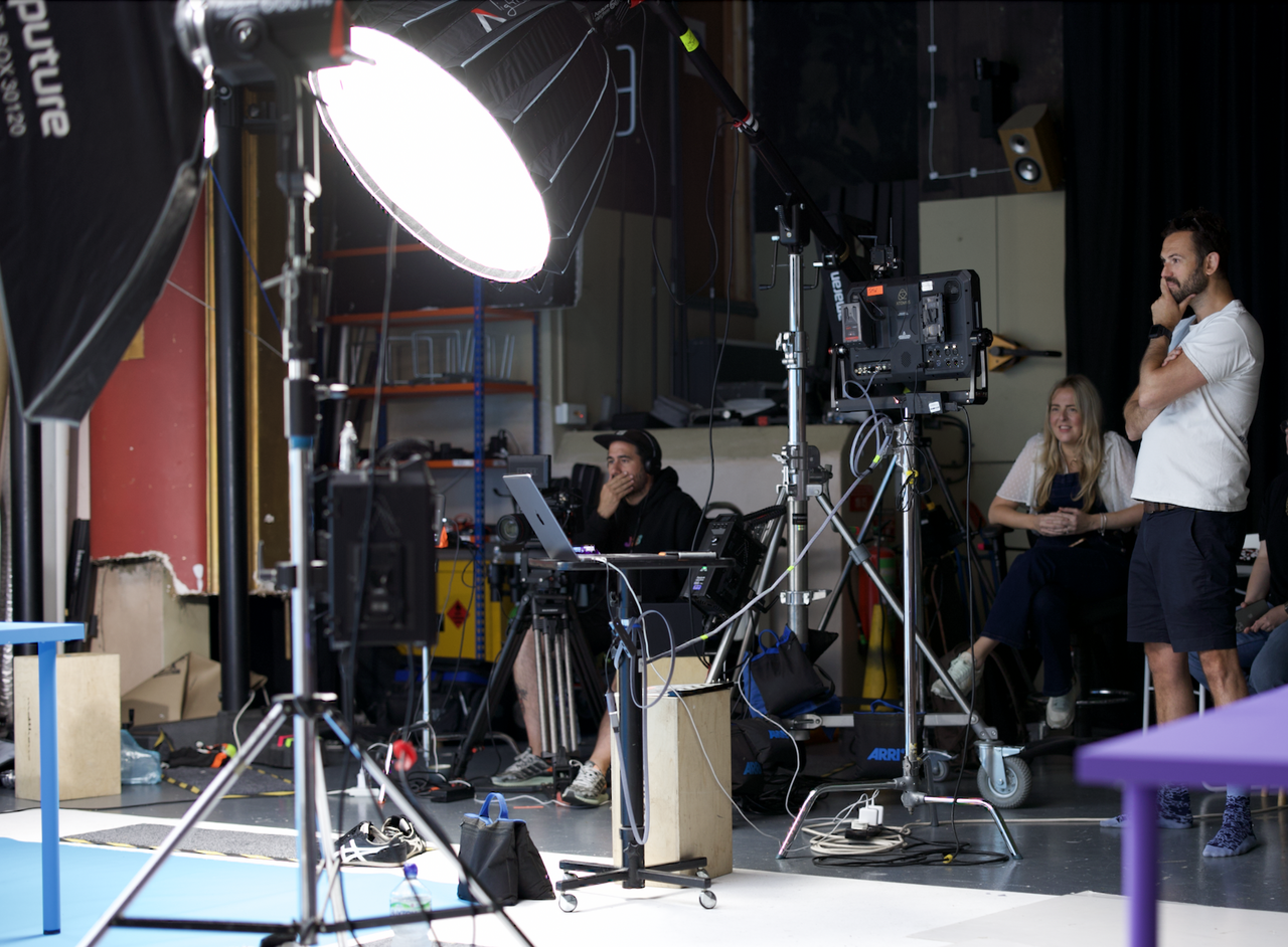 Behind-the-scenes view of a professional video production set with crew, cameras, and lighting equipment in action.