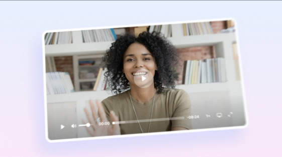 Smiling woman waves at the camera in a paused video frame, set against a modern home office with bookshelves in the background. Play button and video UI elements are overlaid.