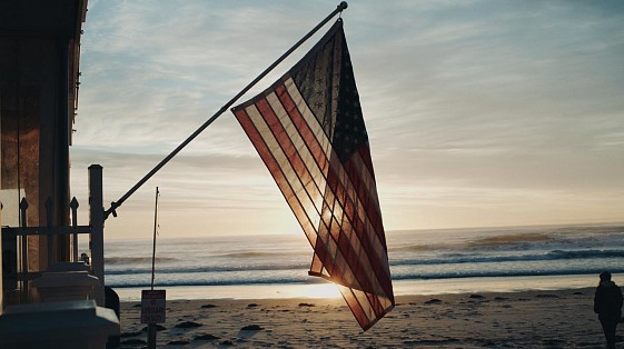 American flag waving at sunrise on a Maine beachfront, filmed for RMS hospitality case study video