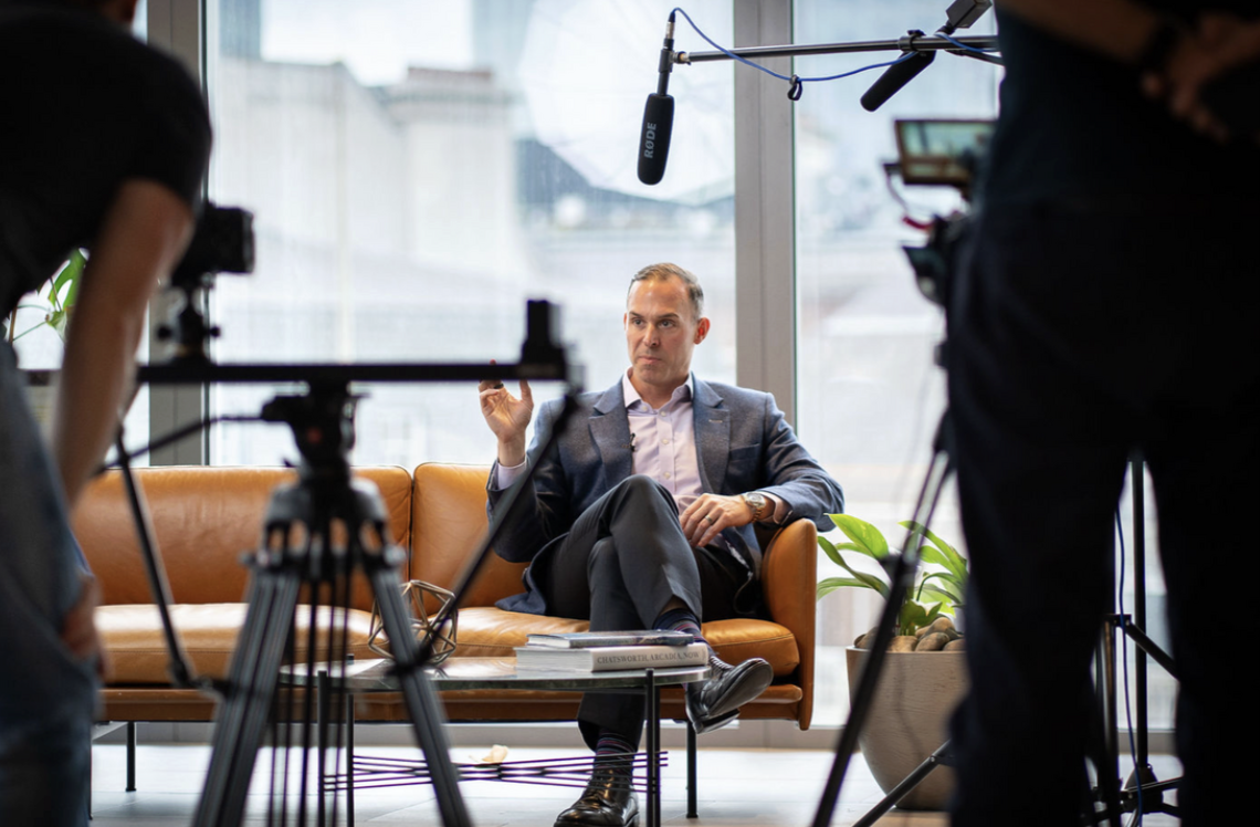 Professional video crew filming a seated executive interview in a modern office setting.