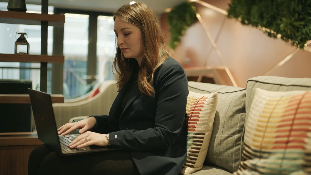 Female hospitality professional working on a laptop in a lounge area during RMS customer testimonial filming in Edinburgh